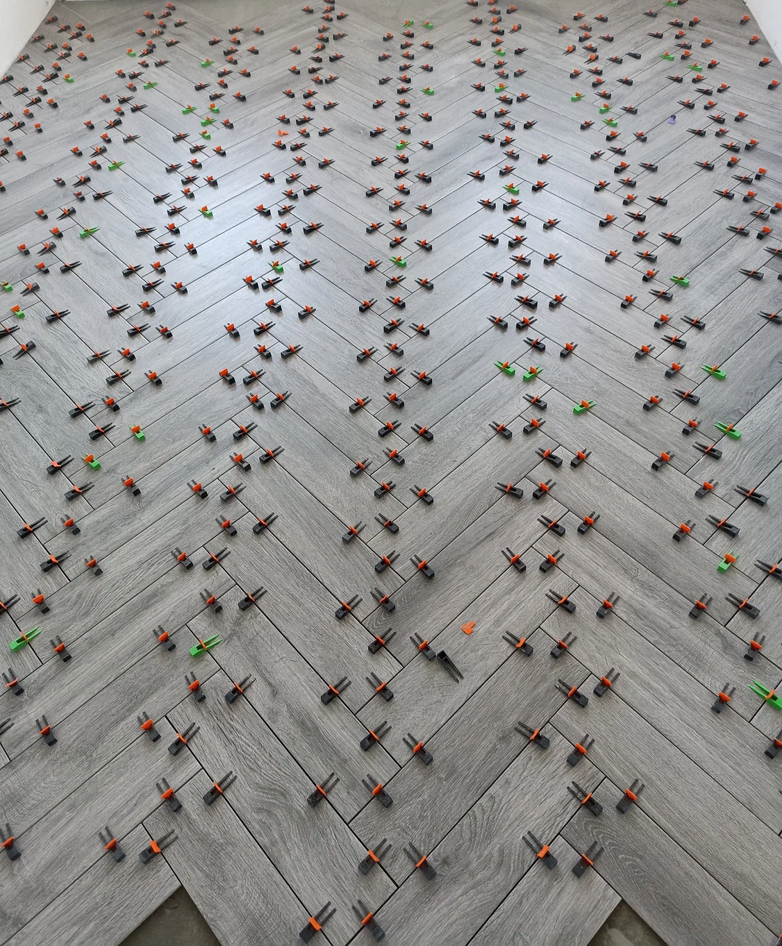 Large-format gray floor tile installation with precision leveling clips